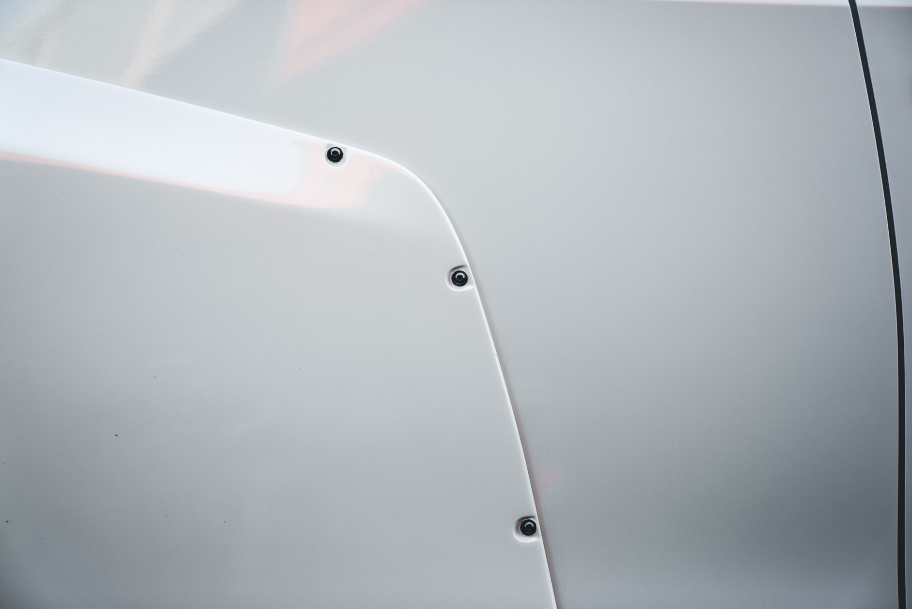 A corrected white panel in full daylight, its surface unbroken and mirror-smooth